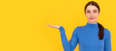 Sarı arka planda bayan portresi. Reklam. Ürün sunan kadın. İzole edilmiş yüz portresi, afiş başlığı posteri ve kopyalanmış kopya alanı