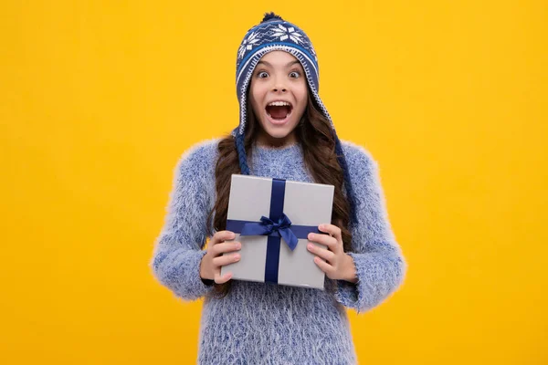 Funny kid girl in winter wear holding gift boxes celebrating happy New Year or Christmas. Winter holiday. Excited teenager girl