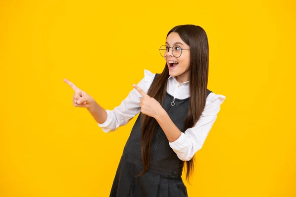 Teenager child pointing to the side with a finger to present a product or idea. Teen girl in casual outfit pointing empty space. Excited face, cheerful emotions of teenager girl