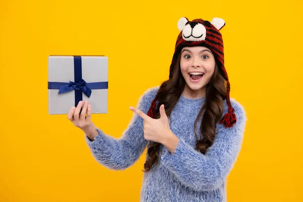 Teenager child in winter wear holding gift boxes celebrating happy New Year or Christmas. Winter kids holiday. Happy teenager, positive and smiling emotions of teen girl.