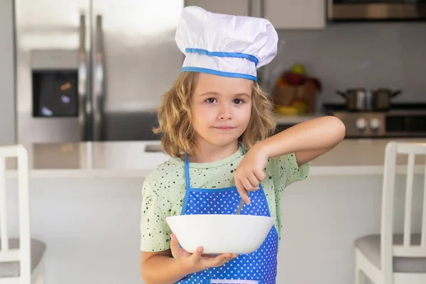 Funny child stand at kitchen table have fun baking, doing bakery preparing food at home kithen