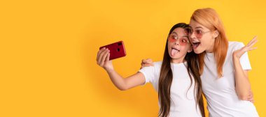 Anne ve kız çocuk afişi, kopyalama alanı, izole edilmiş arka plan. Şaşırmış anne ve kız çocuğu akıllı telefon ve annelik ile selfie çekiyorlar.