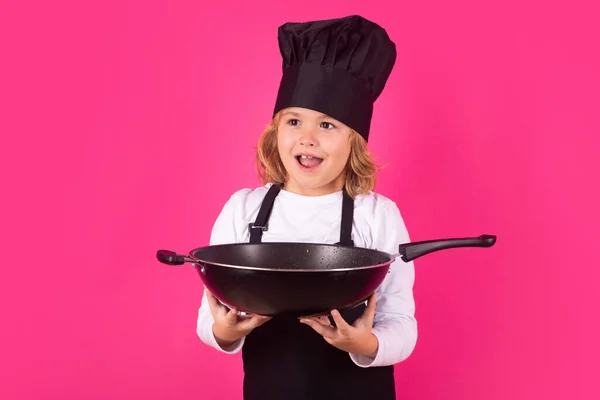 Kid chef cook cookery with pan. Child chef cook, studio portrait. Kids cooking. Teen boy with apron and chef hat