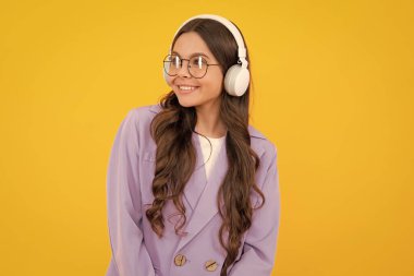 Modern kablosuz kulaklıklı bir genç, müzik dinleyerek müzik dinliyor, sarı stüdyo arka planında en sevdiği müziği dinliyor.