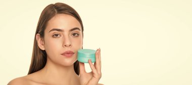 Temizleme fırçası. Bayan kozmetik ürünü sunuyorum. Kadın yüz kremi kullanıyor. Kadın yüzü, yakın portre, kopyalanmış afiş