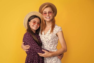 Sarı arka planda hasır şapkalı anne ve kız.