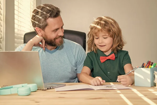 bearded dad or school private tutor teaching boy son with modern laptop, family.