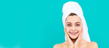 Güzel yüzlü kadın, yüz portresi. Mutlu genç kız mavi arka plana yüz kremi sürüyor. Güzel kadın, izole edilmiş yüz portresi, taklit alanı olan pankart.