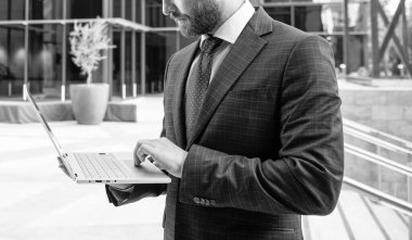 Modern açık hava dizüstü bilgisayarı ve teknolojisi üzerinde resmi kıyafet işindeki kırpılmış bir iş adamı..