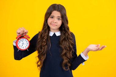 Child teenager girl with alrm clock isolated on yellow background. Time and deadline concept