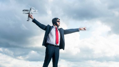 Takım elbise ve pilot şapkalı oyuncağın gökyüzü arka planında.