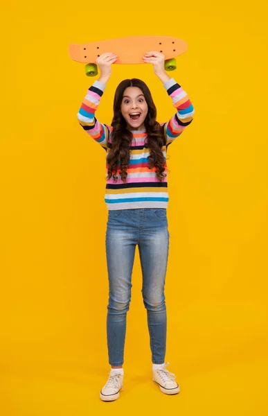 Teen school girl with skateboard on studio isolated background. Schoolgirl trend, urban teenager style. Happy teenager, positive and smiling emotions of teen girl