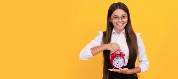 happy nerd child with alarm clock. school kid in uniform and glasses showing time. you are late. Teenager child with clock alarm, horizontal poster. Banner header, copy space
