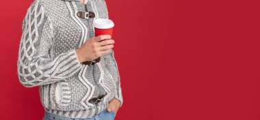 Gülümseyen yakışıklı adam süveter giy ve kış şapkası tak kahve fincanı, kış.