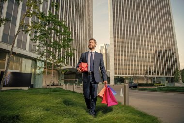 Karizmatik, takım elbiseli, olgun iş adamının hediye paketini ve hediye kutusunu ofisin dışında tutmasına sevindim..