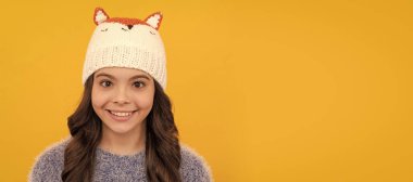 happy child in sweater and hat on yellow background, winter. Child face, horizontal poster, teenager girl isolated portrait, banner with copy space