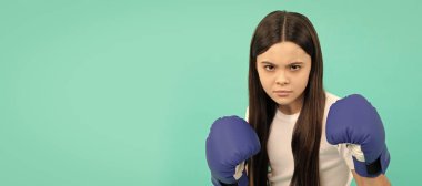 concentrated kid boxer punching in boxing gloves during sport training, copy space, determination. Horizontal poster of isolated child face, banner header, copy space