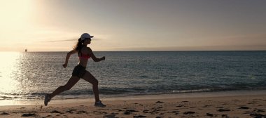 Kadın deniz sahilinde koşup zıplıyor. Koşmak benim favorim. Formda kız deniz kenarında koşuyor. Kadın koşucu. İz sürüyor. Koşu faaliyetleri