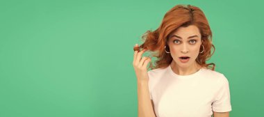 surprised redhead girl with curly hair on blue background, surprise. Woman isolated face portrait, banner with copy space