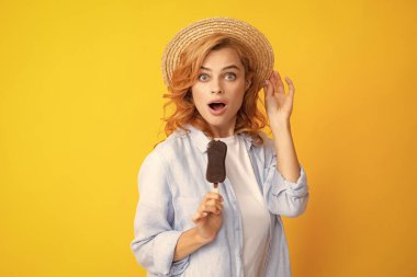 Moda portresi, sarı arka planda dondurması olan havalı genç bir kadın. Genç küstah hippi kız yapışmak için dondurma yiyor. Şaşırmış kadın yüzü