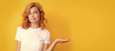 Üzerinde kafa yoran kızıl saçlı kadın sarı arka planda fotokopi alanı olan ürünler sunuyor. Güzel kadın, izole edilmiş yüz portresi, taklit alanı olan pankart.