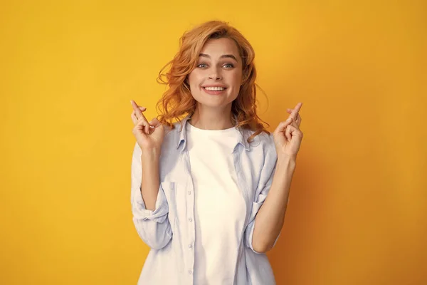 Portrait of funny woman with crossed fingers for good luck, isolated background. Headshot of glad woman crosses fingers with positive expression, believes in good luck and success