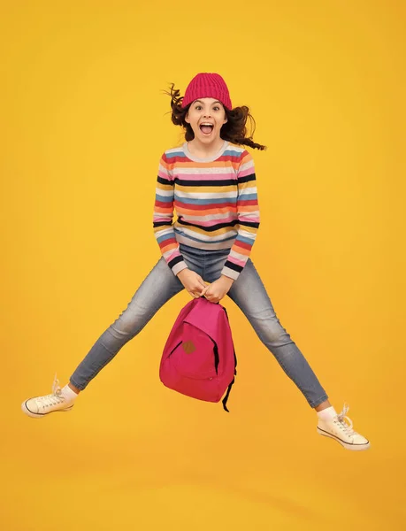 Autumn school. Teenager school girl with backpack in autumn clothes on yellow isolated studio background. Crazy jump and run, jumping kids