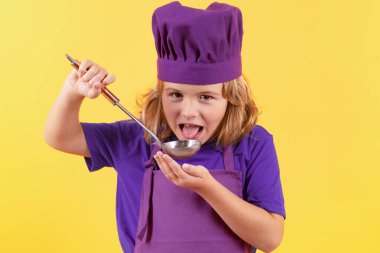 Mutfak kepçesiyle aşçı çocuk, stüdyo portresi. Çocuk aşçı, stüdyo resmi. Çocuklar yemek yapıyor. Önlüklü ve aşçı şapkalı genç çocuk.