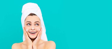 Cilt bakımlı güzel kadın. Genç bayanın mavi arka plana yüz kremi sürmesine şaşırdım. Güzel kadın, izole edilmiş yüz portresi, taklit alanı olan pankart.