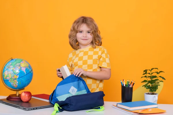 Back to school. Funny little child from elementary school puts school supplies in a backpack. Preparation for school. Education. Kid study and learning
