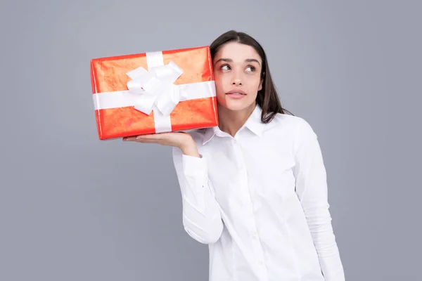 Woman with gift. Portrait of excited young girl holding gift box, isolated grey background. Pretty girl with present