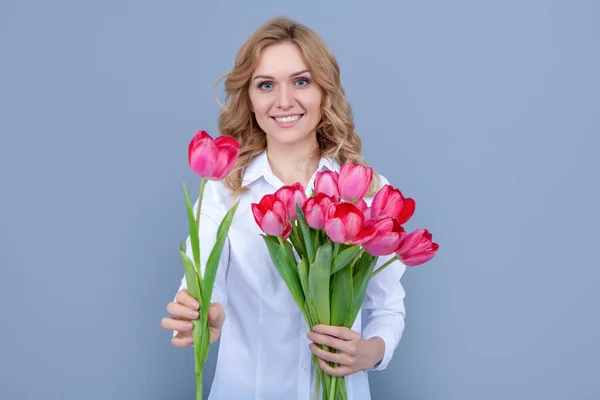 young woman smile give spring tulip flowers on grey background.