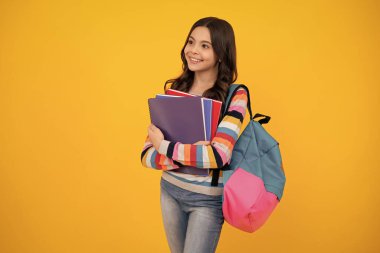Back to school. Teenager schoolgirl hold book and copybook ready to learn. School children on isolated yellow studio background. Happy teenager, positive and smiling emotions of teen girl