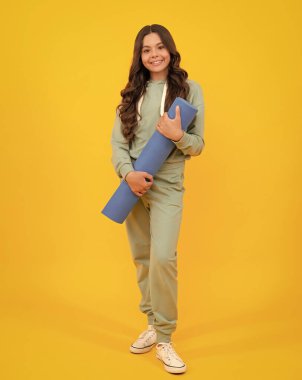 Spor üniformalı genç kız, stüdyoda poz veriyor. Kapüşonlu kapüşonlu şık takım elbiseli bir çocuk. Spor giyim ve yoga kıyafetleri reklamı. Sağlıklı çocuk yaşam tarzı, spor