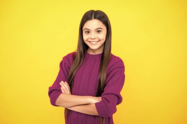 Sarı arka planda izole edilmiş çapraz kollu genç kız portresi. Çocuk yaşam tarzı konsepti