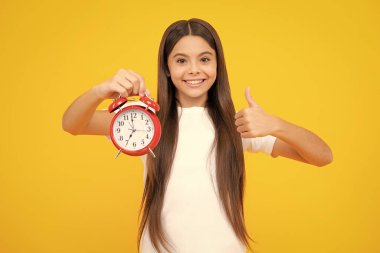 Punctual teen girl checking time. Child with alarm clock showing time. Happy teenager portrait. Smiling girl