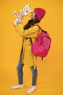 Schoolgirl 12, 13, 14 years old with toy. School children cuddling favorite toys on yellow background. Happy autumn teenager, positive and smiling emotions of teen schoolgirl
