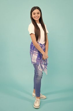 Full length of attractive cheerful teenager child girl in casual fashion clothes over blue isolated background. Happy teenager, positive and smiling emotions of teen girl