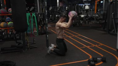 Sporcuların spor salonunda spor yapmaları. Sporcunun spor salonunda top egzersizi var. Sporcu topuyla fitness antrenmanı.