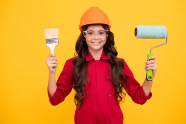 İnşaat alanında küçük miğfer ustası. Fırça aletli ya da boya silindirli genç kız ressam. Tamir işinde olan bir çocuk. Yenileme konsepti. Mutlu gülümseyen kız