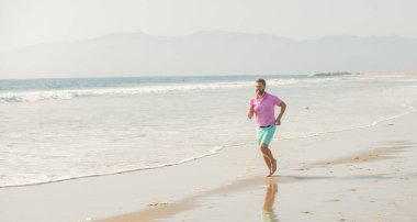 Spor adamı yaz tatilinde sahilde koşuyor. Eğitim, kopyalama alanı, özgürlük için..