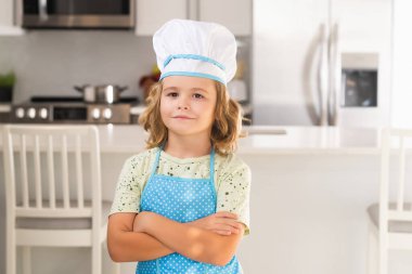 Mutfaktaki komik çocuk şefin portresi. Aşçı aşçı çocuk mutfakta yemek hazırlıyor. Çocuk lezzetli yapıyor. Yemek pişirme