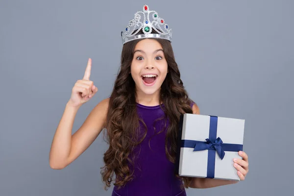 Excited face, cheerful emotions of teenager girl. Teenager child holding gift box on isolated grey background. Gift for kids birthday. Christmas or New Year present box
