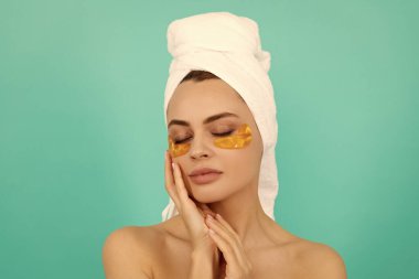 Genç bayanın yüzünde havluyla kolajen altın göz bantları var..