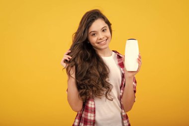 Genç kız şişe şampuanı ya da duş jeli gösteriyor. Saç kozmetik ürünü. Reklam için şişe fotokopi alanı oluşturun. Mutlu ergen, pozitif ve gülümseyen genç kız duyguları