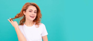 Mavi arka planda kıvırcık saçlı, pozitif kızıl kız. İzole edilmiş yüz portresi, kopyalama alanı olan pankart