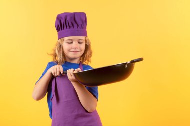 Çocuk tencereyle yemek pişiriyor. Şef çocuk sağlıklı yemek hazırlıyor. Şef şapkalı çocuk portresi