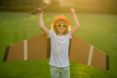 Çocuk özgürlüğü ve tasasız. Mutlu çocuk dışarıda oynuyor. Çocuk kağıt kanatlarla eğleniyor.