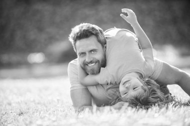 Mutlu baba ve oğul parkta eğleniyor. Aile değeri. Çocukluk ve ebeveynlik. Ebeveyn, küçük çocuk çimlerin üstündeyken rahatlar. Baba ve çocuk yaz günü. Ebeveynlik ve babalık. Babalar Günü.