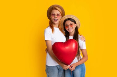 Anneni sev. Anne ve kızı kalp balonu tutuyor. Sarı arka planda aşk balonu tutan mutlu anne ve kız.